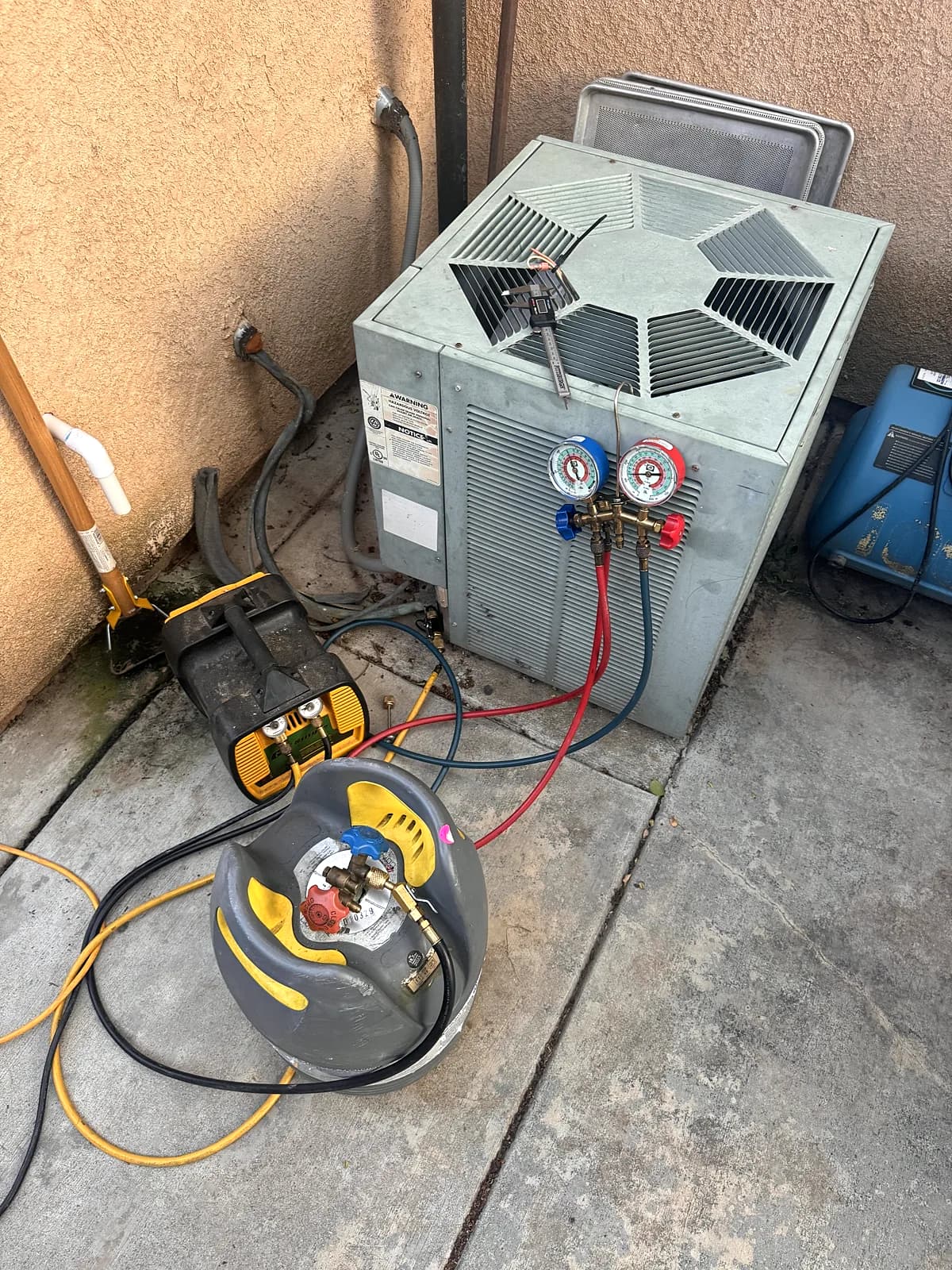 Gauges and a recovery machine connected to an AC condenser during a replacement