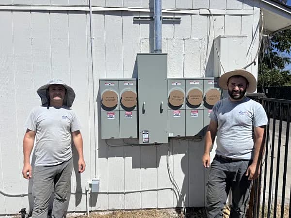 Two ProLine electricians next to a finished five-meter main panel